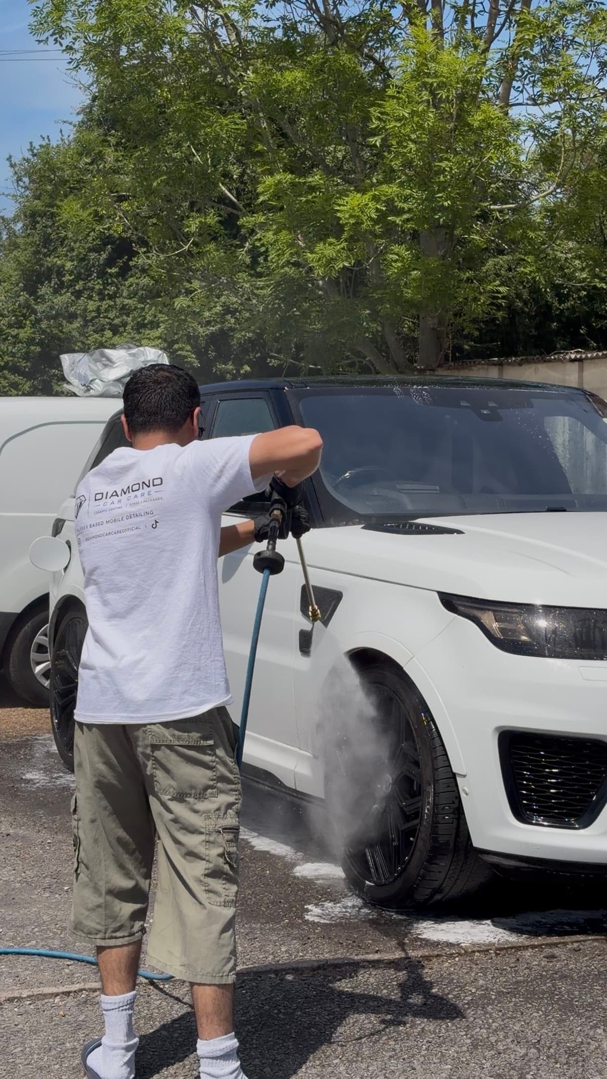 Diamond Car Care detailer in branded workwear pressure-washing a white Range Rover Sport